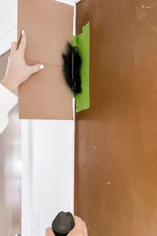 spray painting door hinge for DIY door upgrade