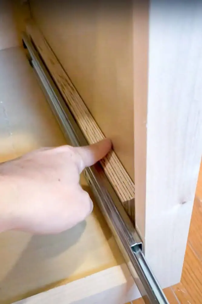 Gap between drawer slide and side of cabinet filled with wood piece
