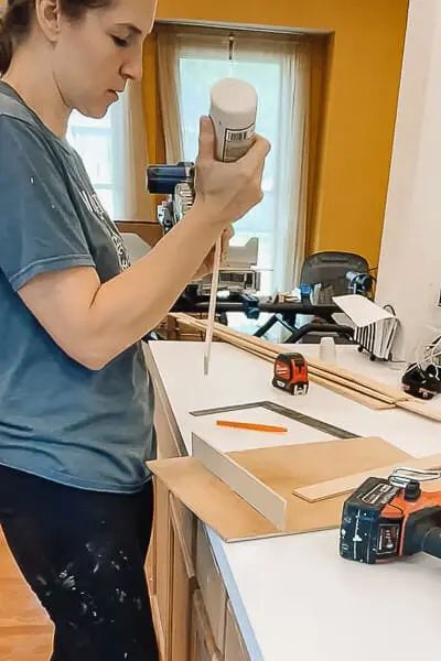 Applying wood glue to a wooden drawer divider for a DIY organization project.