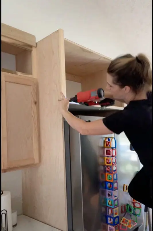 Woman using brad nailer to install trim.