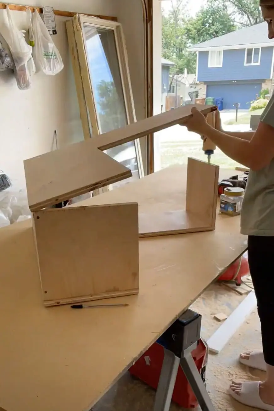 Woman using wood glue while building a kitchen cabinet.