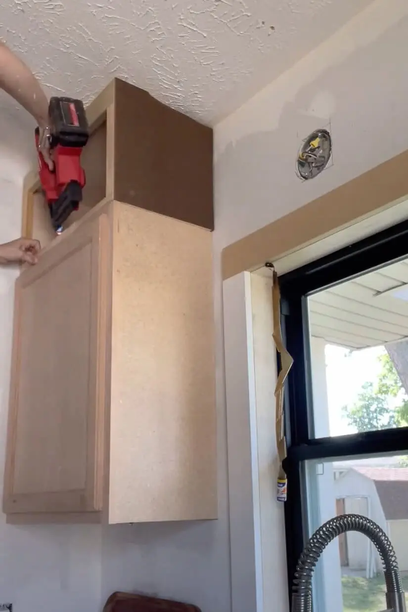 Woman installing kitchen cabinet.