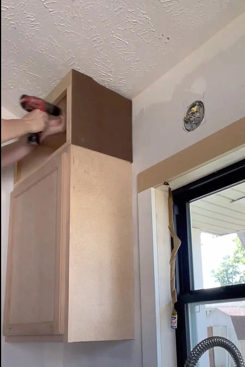 Woman installing kitchen cabinet.