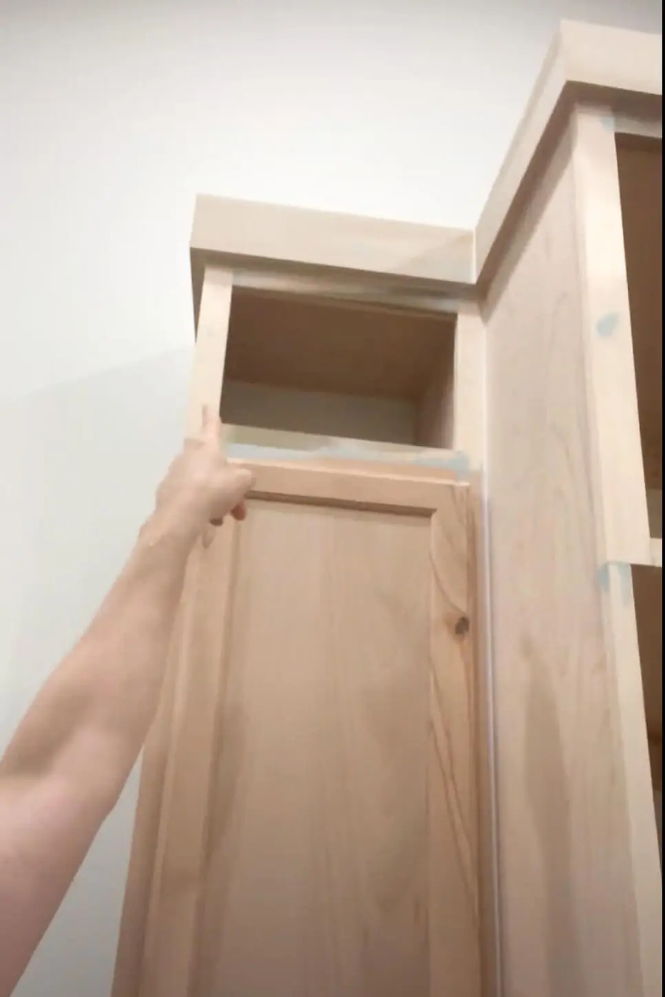 Filling seams on DIY kitchen cabinets with bondo and caulk.