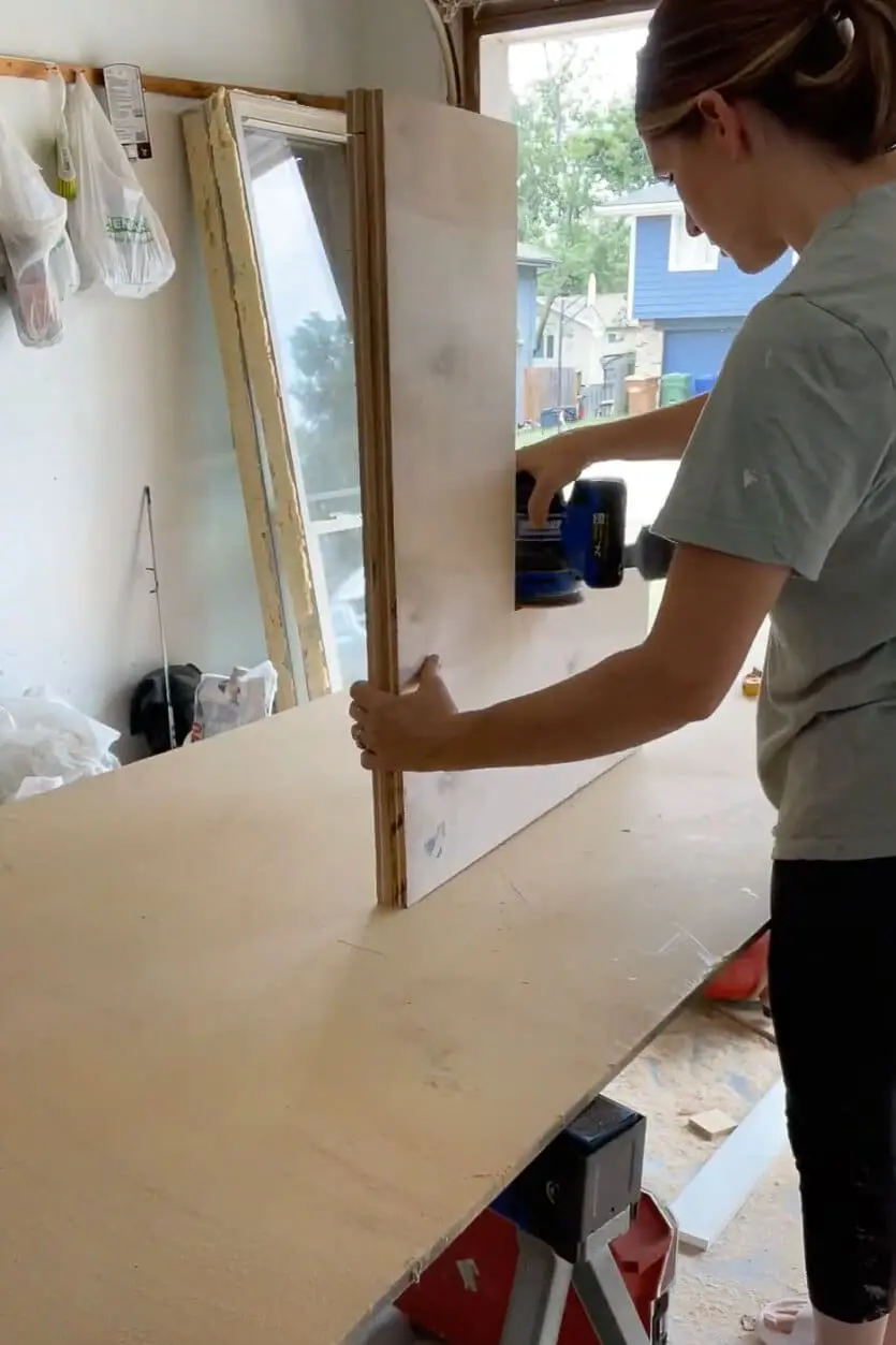 Woman sanding wood with electric handheld sander.