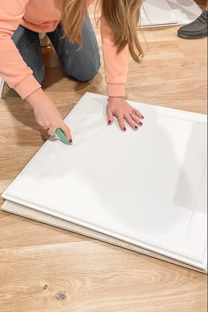 Cutting a drop ceiling tile with a razor
