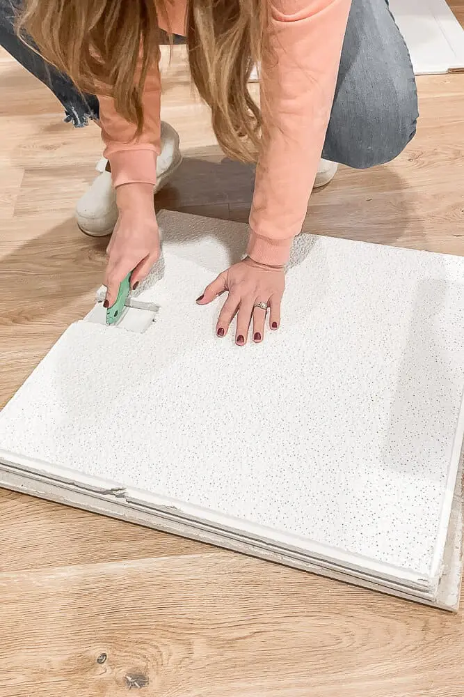 Cutting a drop ceiling tile with a razor