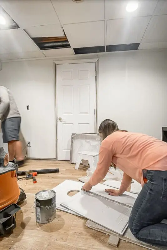 woman installing a drop ceiling tile