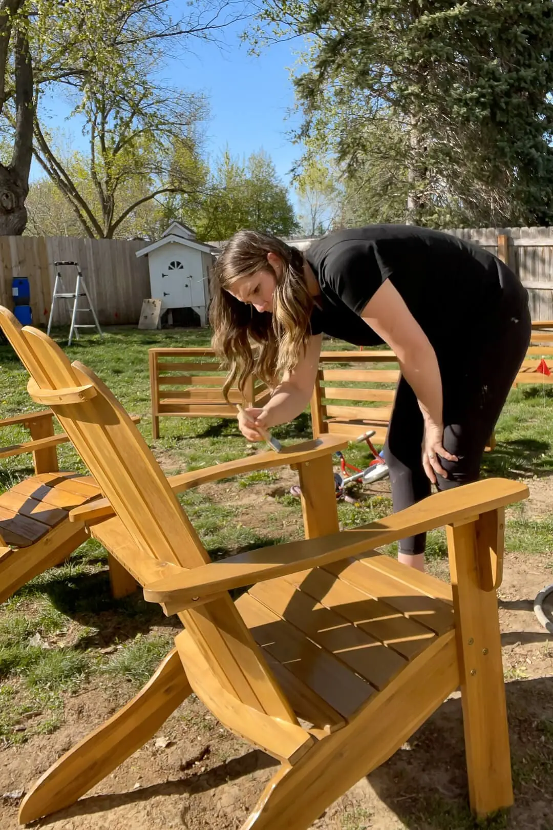Using a sprayer to apply clear sealant to protect outdoor patio furniture.