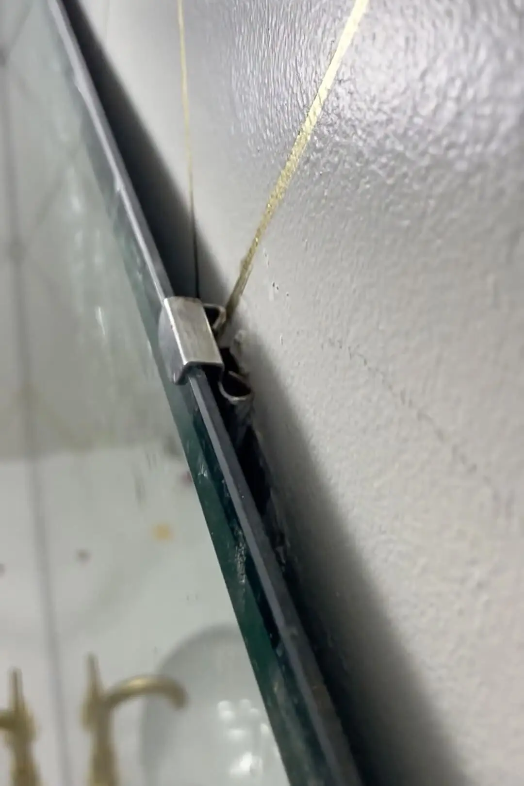Clips are being used to hold the bathroom mirror to the wall.