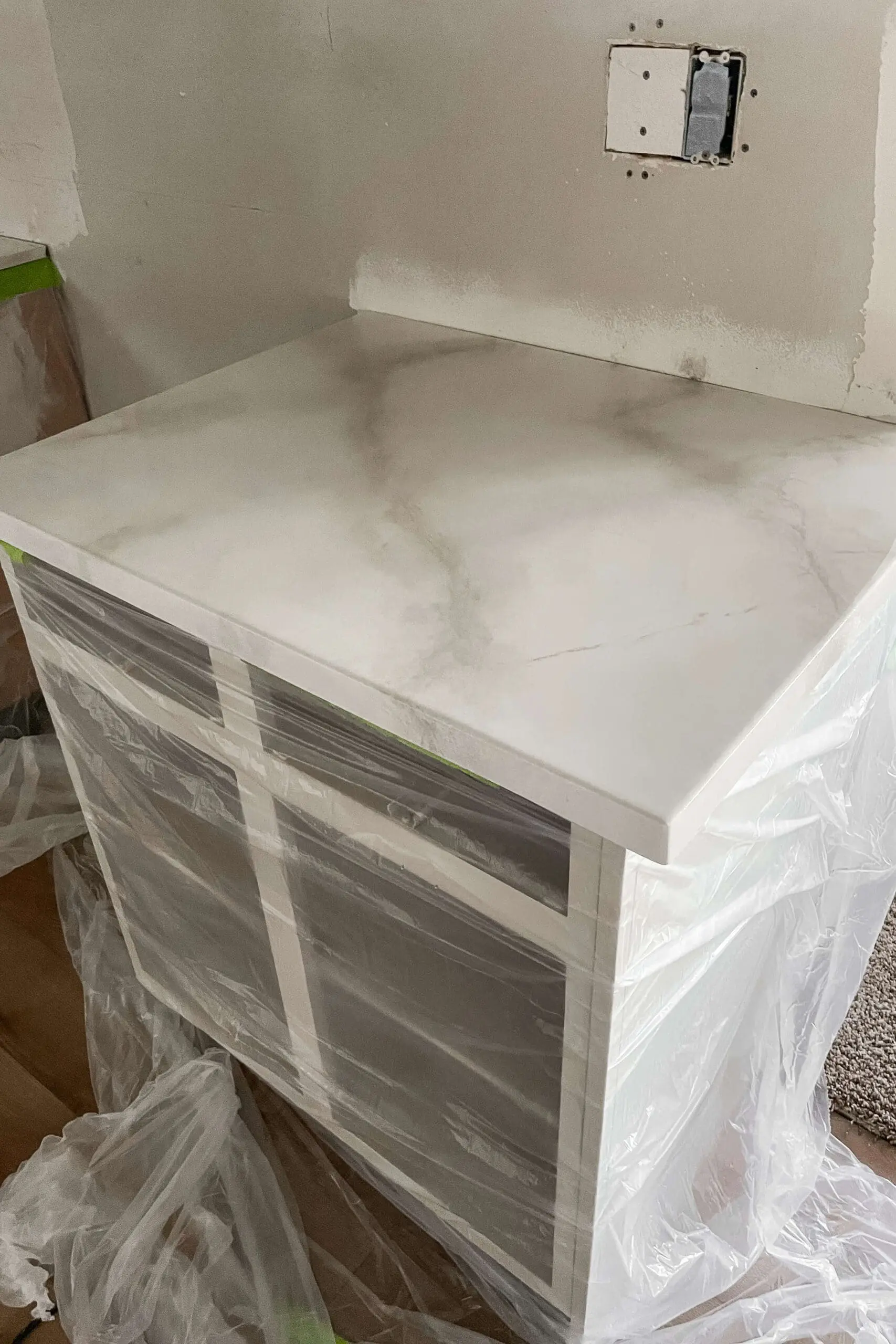 Masking before pouring epoxy on faux marble kitchen countertops.