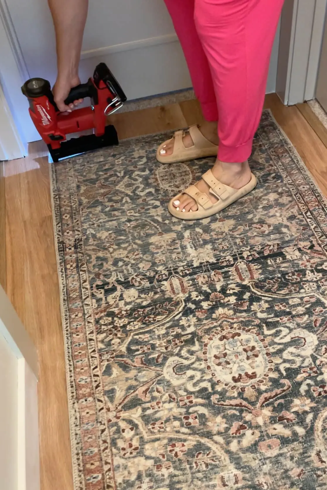 Stapling a carpet runner rug down in a hall. 