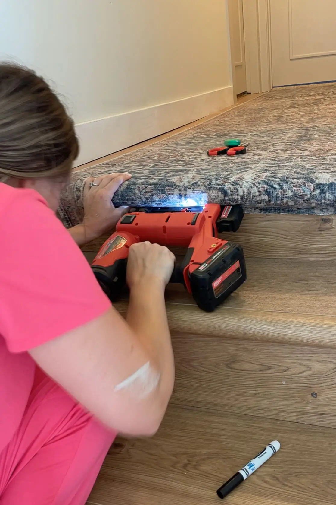 Using a stapler to attach a carpet runner rug to stairs. 