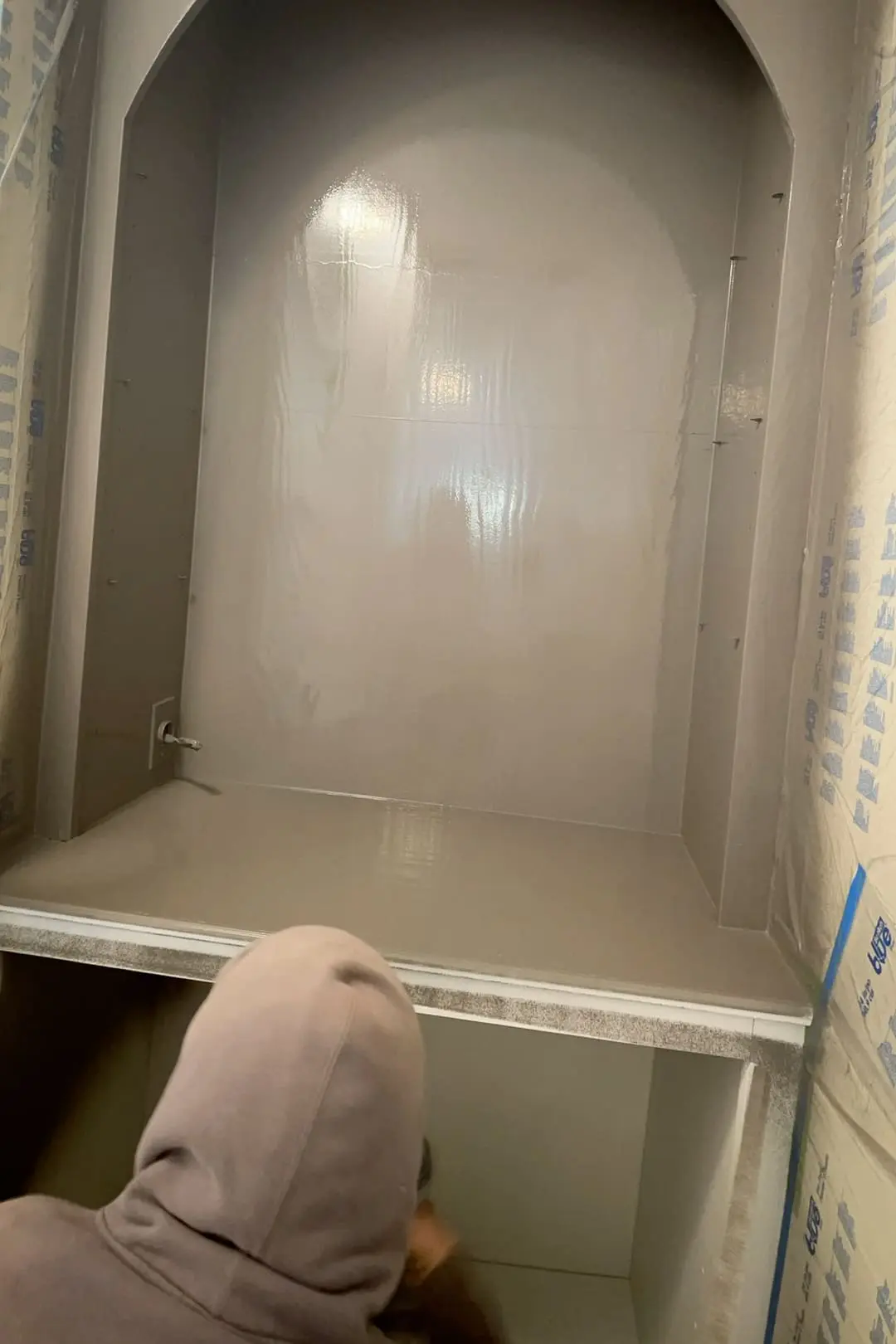 Painting built-in living room shelves with a paint sprayer.