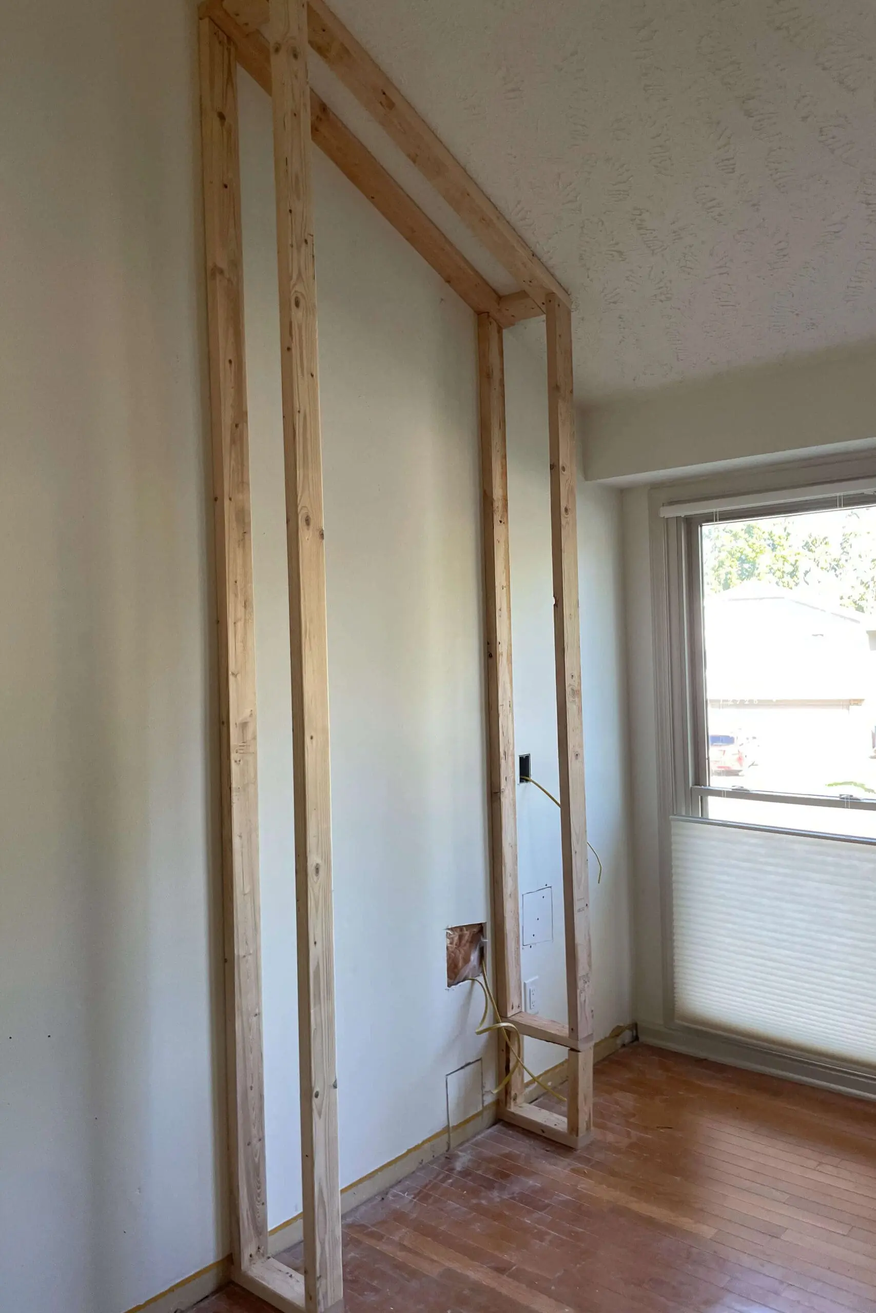 Vertical framing studs secured to ceiling and floor to outline the fireplace surround.
