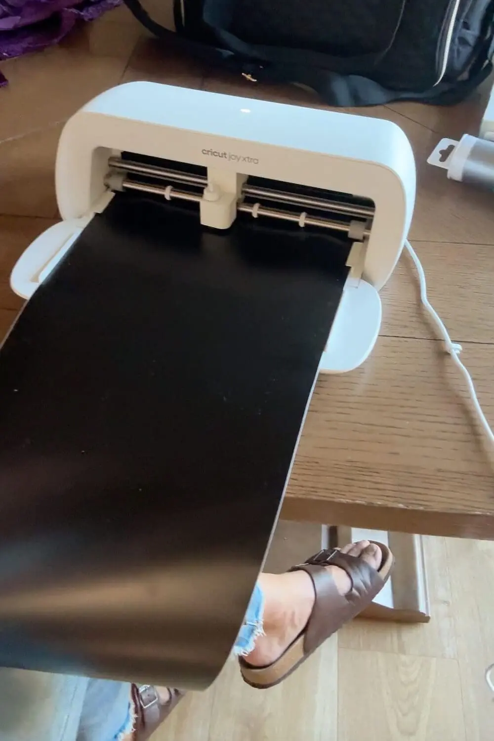 Cricut cutting black vinyl to make eyes and a smile for the sheet ghost faces.