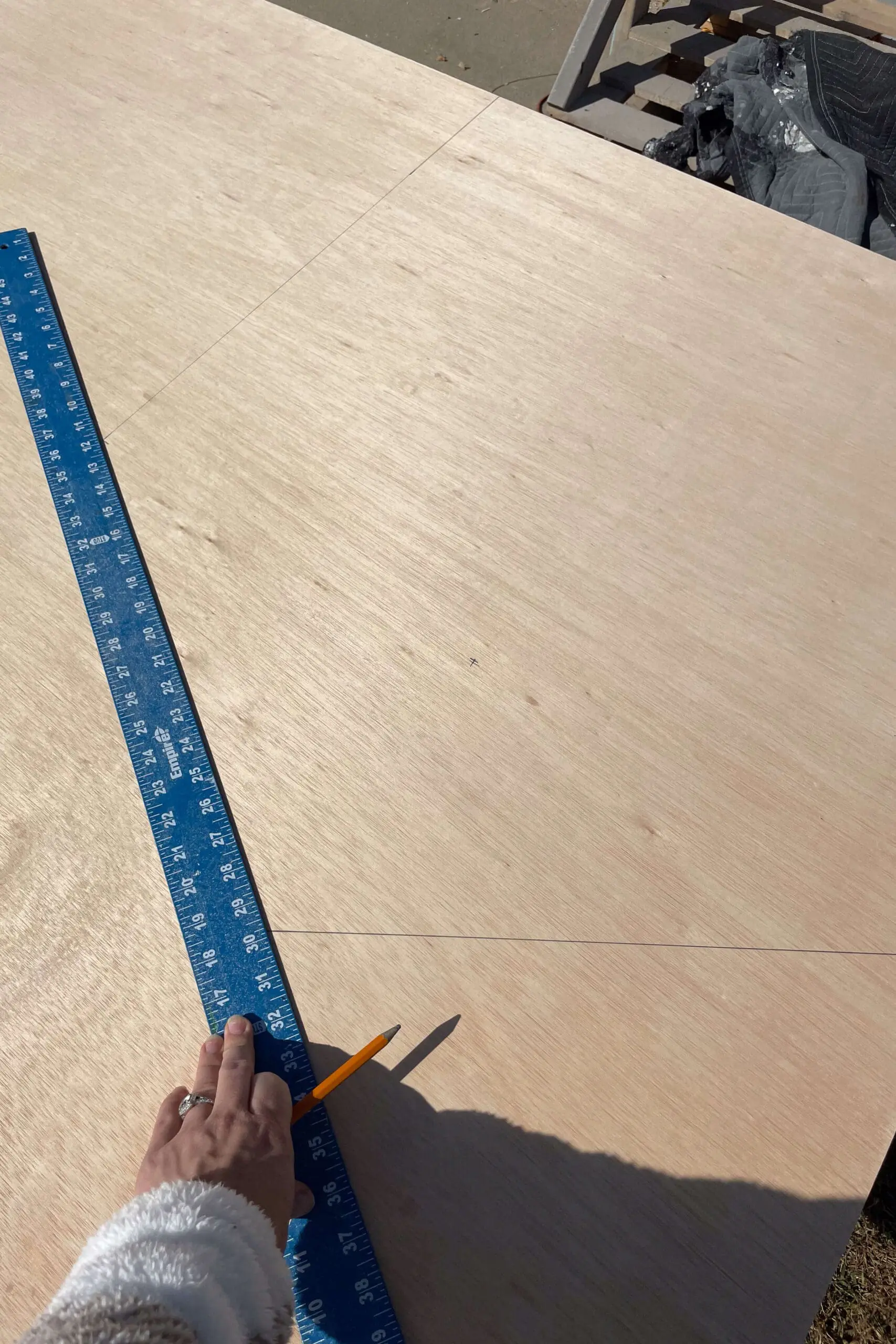 Hand measuring and marking lines on plywood using a ruler. This careful planning step ensures accuracy in each wooden piece.