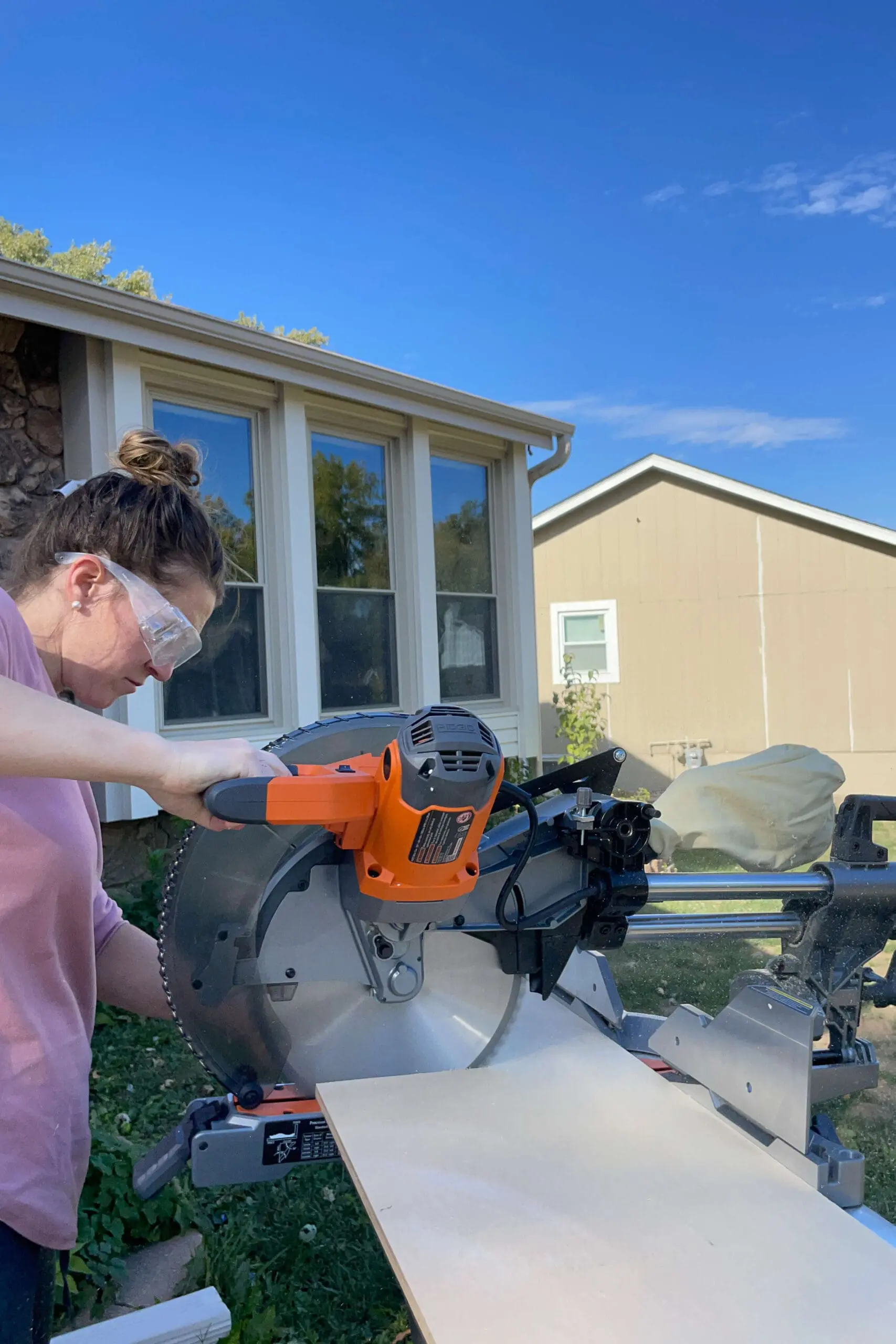 Person using a miter saw to cut plywood outdoors. The detailed cutting process ensures each piece is accurately sized for assembly.