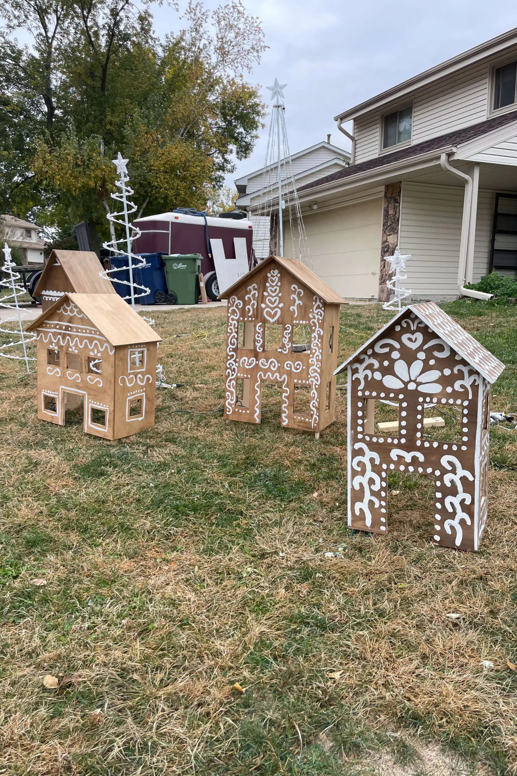 Wooden gingerbread houses decorating the front yard during the daylight.