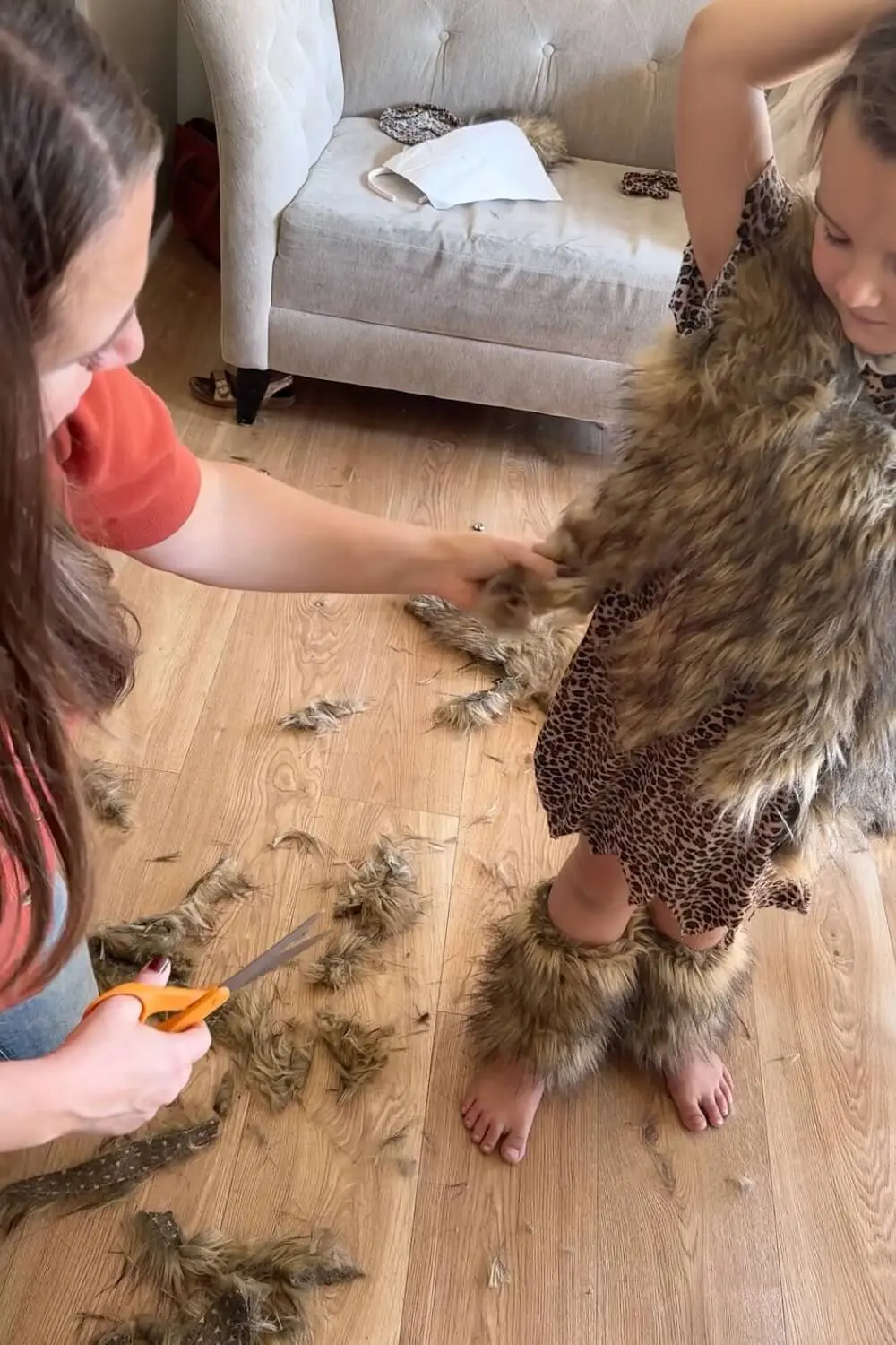 Adult trimming a sleeve opening on a child’s leopard-print tunic for better fit.