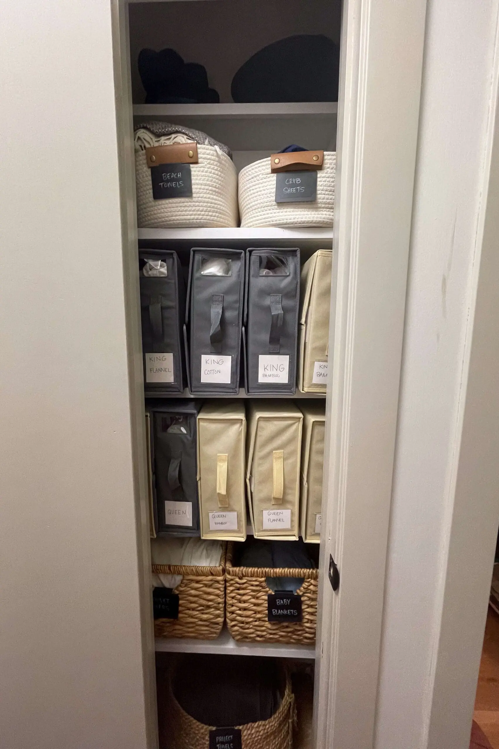 Well-organized linen closet with labeled bins for neatly storing bed linens, pillowcases, and baby blankets.