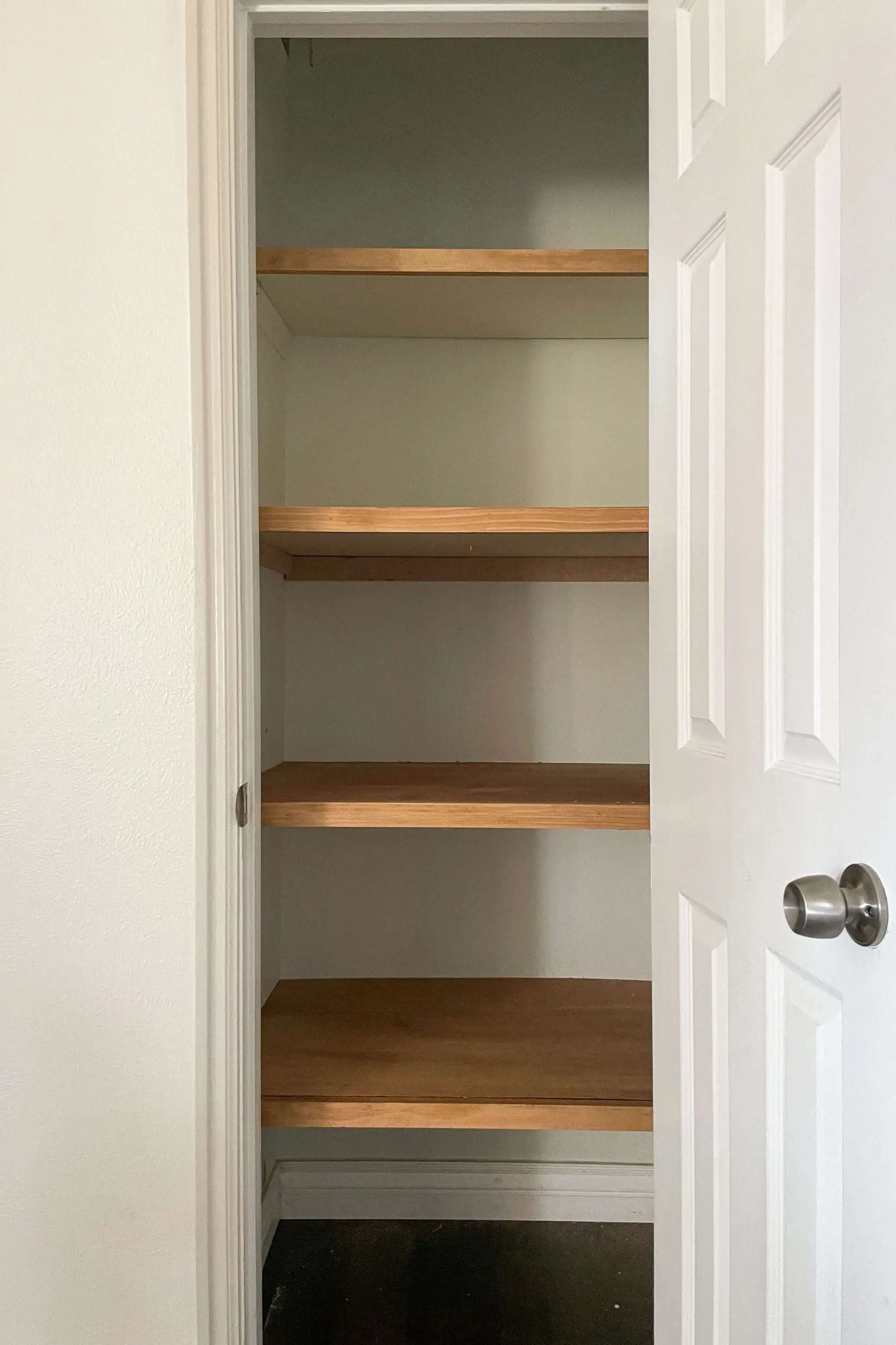 Closet transformation in progress with custom-built wooden shelves installed for better organization and storage.