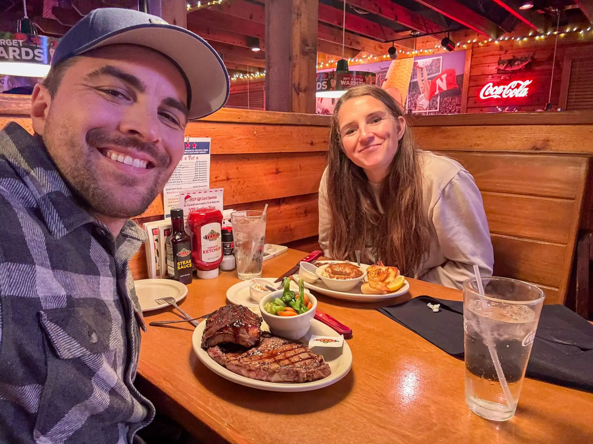 A couple enjoying a carnivore-friendly meal at a steakhouse, featuring a ribeye steak, ribs, and sides.