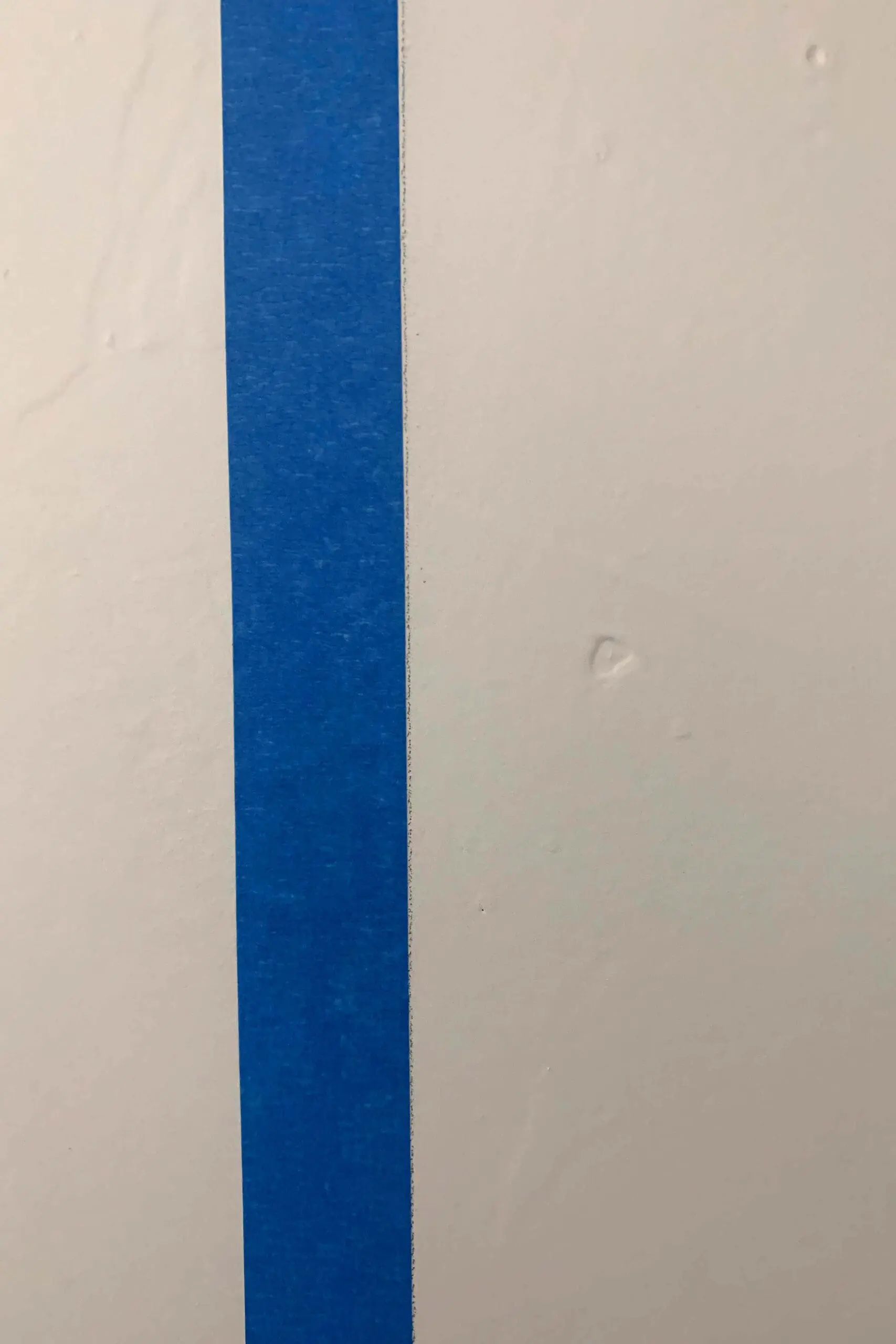 Close-up view of painter’s tape on a wall surface during prep for painting a buffalo plaid accent wall