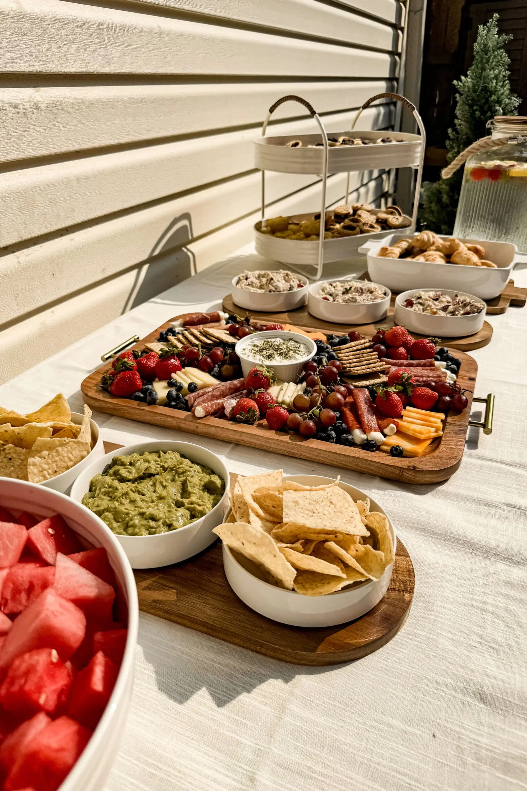 Close-up of a vibrant charcuterie board, guacamole, chips, and fruit on a backyard buffet table—ideal for summer entertaining.