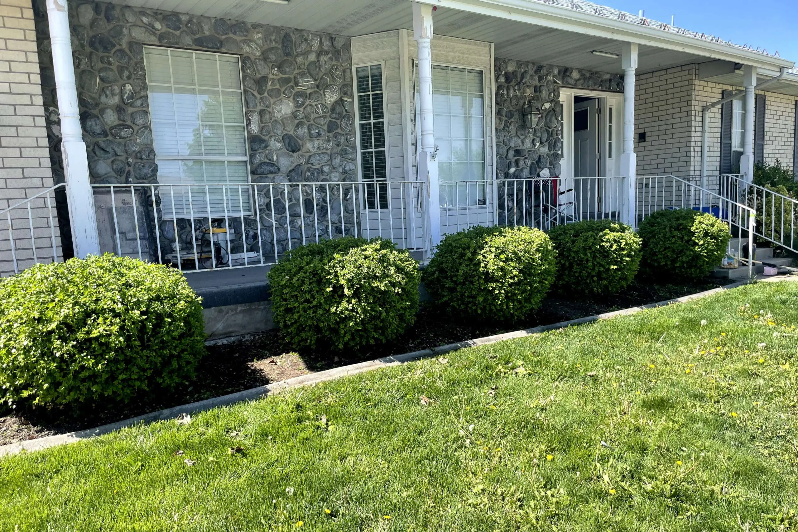 Stone house exterior with white framed windows and metal railings before update.