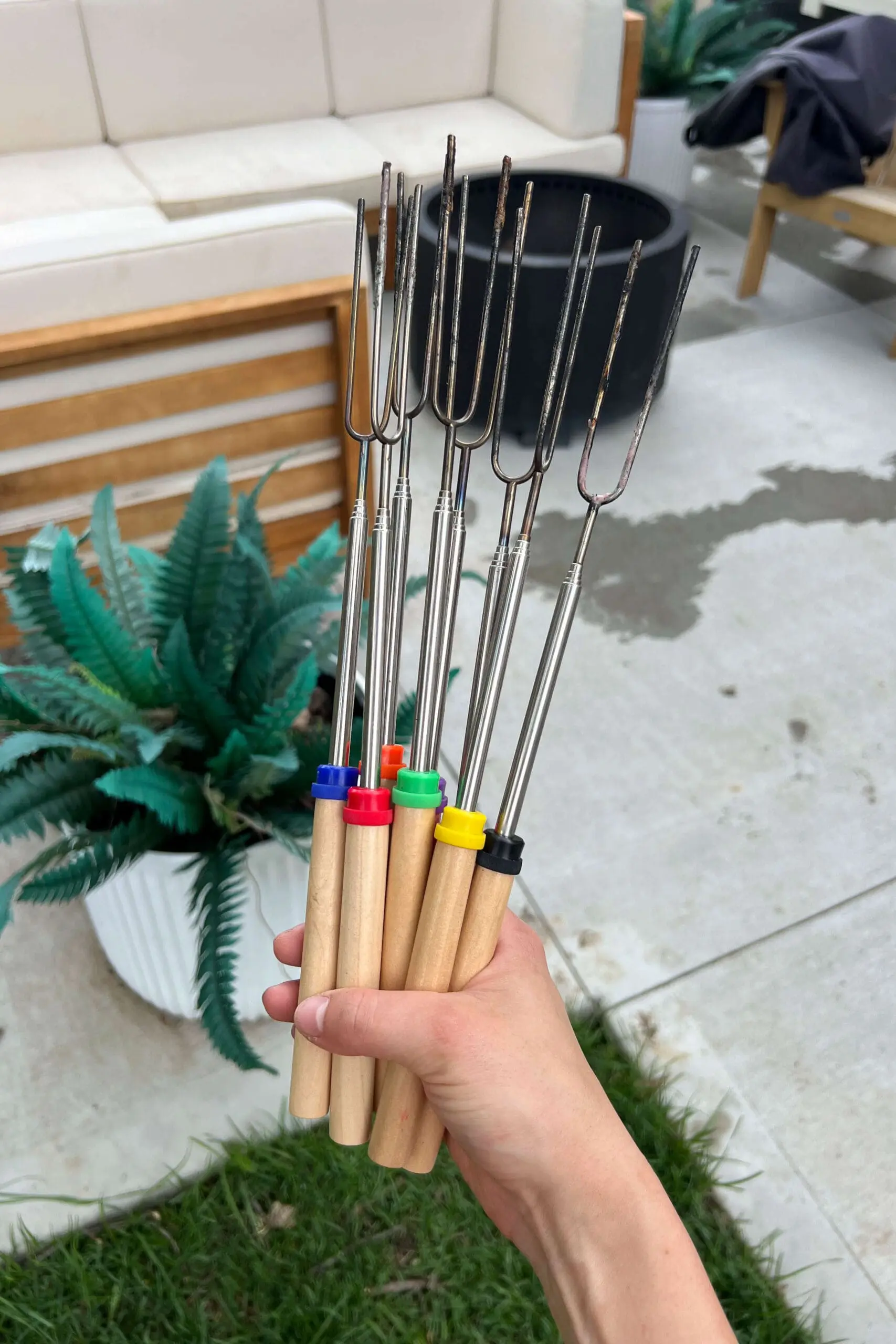 Set of extendable marshmallow roasting sticks held outside, ideal for backyard fire pits and outdoor s’mores nights.