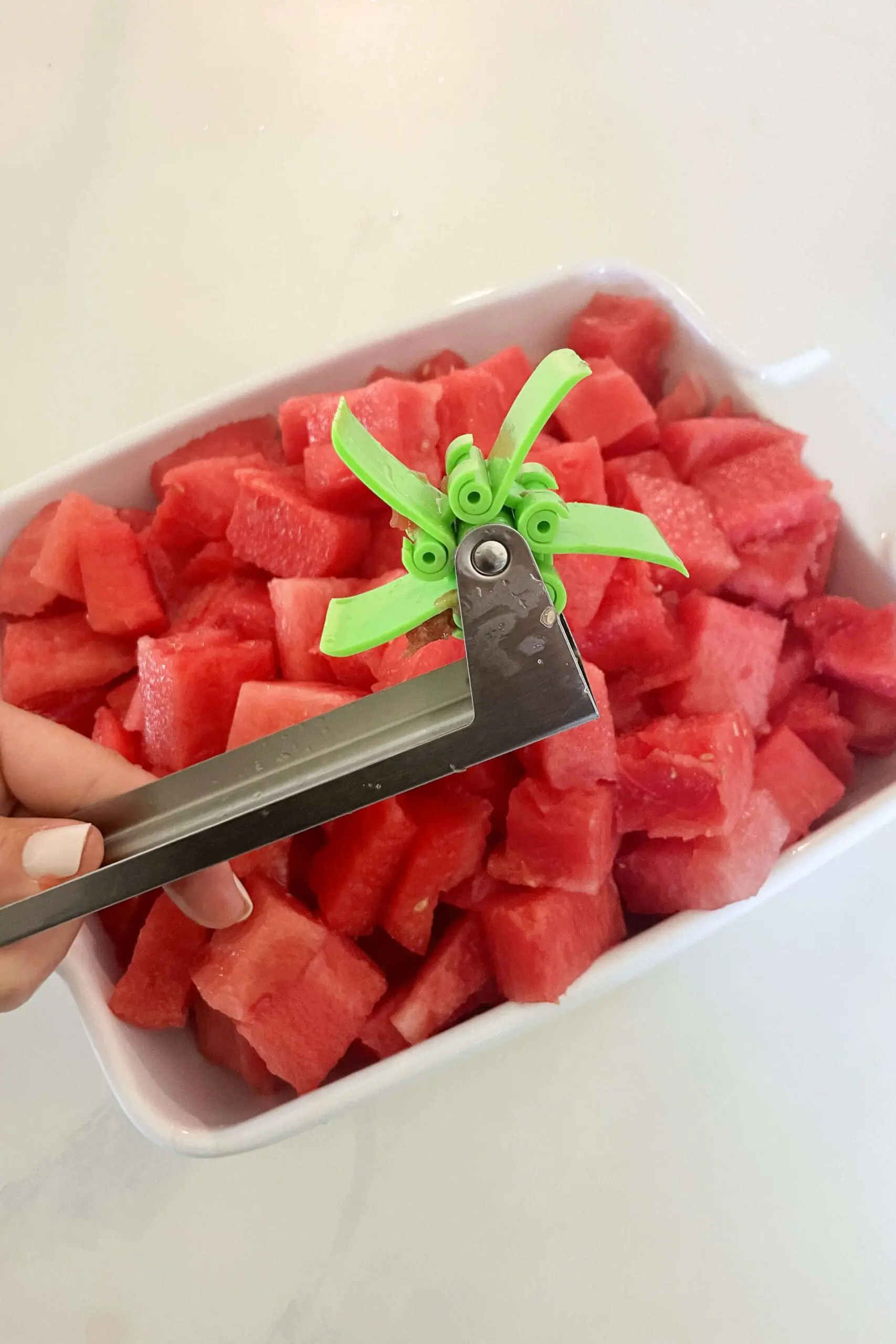Close-up of a stainless steel watermelon slicer tool cutting cubes into a bowl—summer snack hack for outdoor hosting.