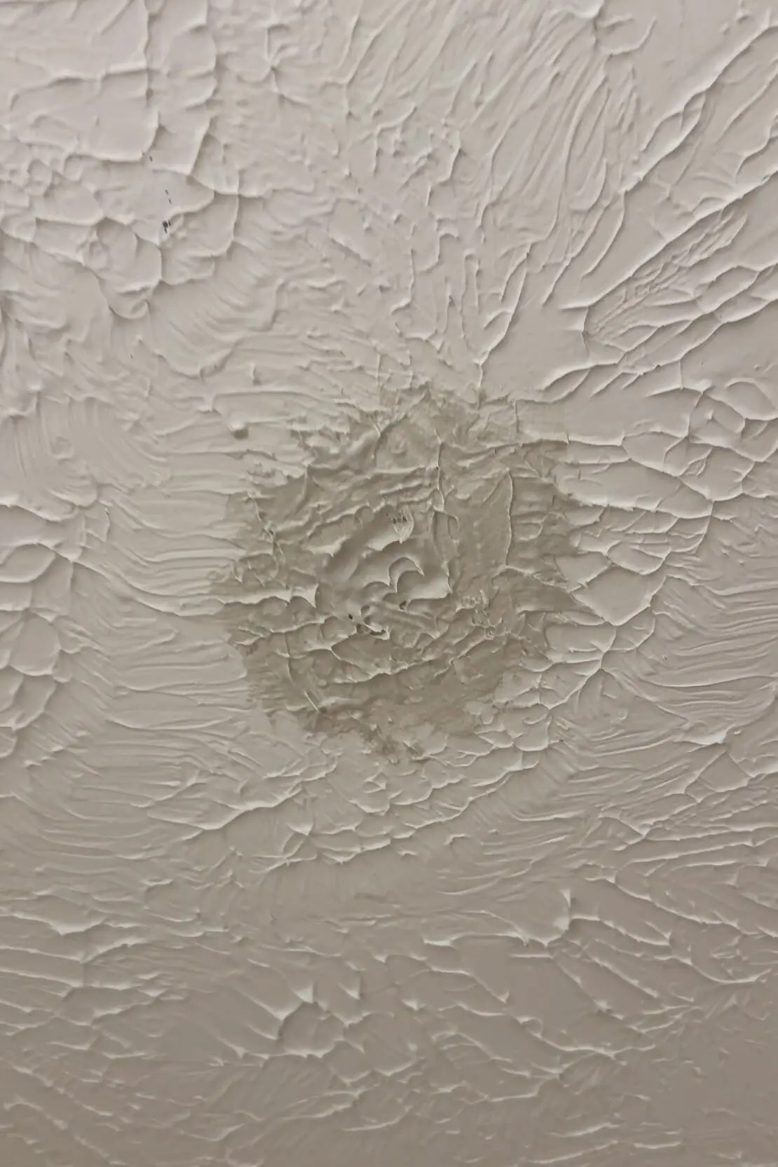 Textured ceiling with dried joint compound patch before final paint touch-up