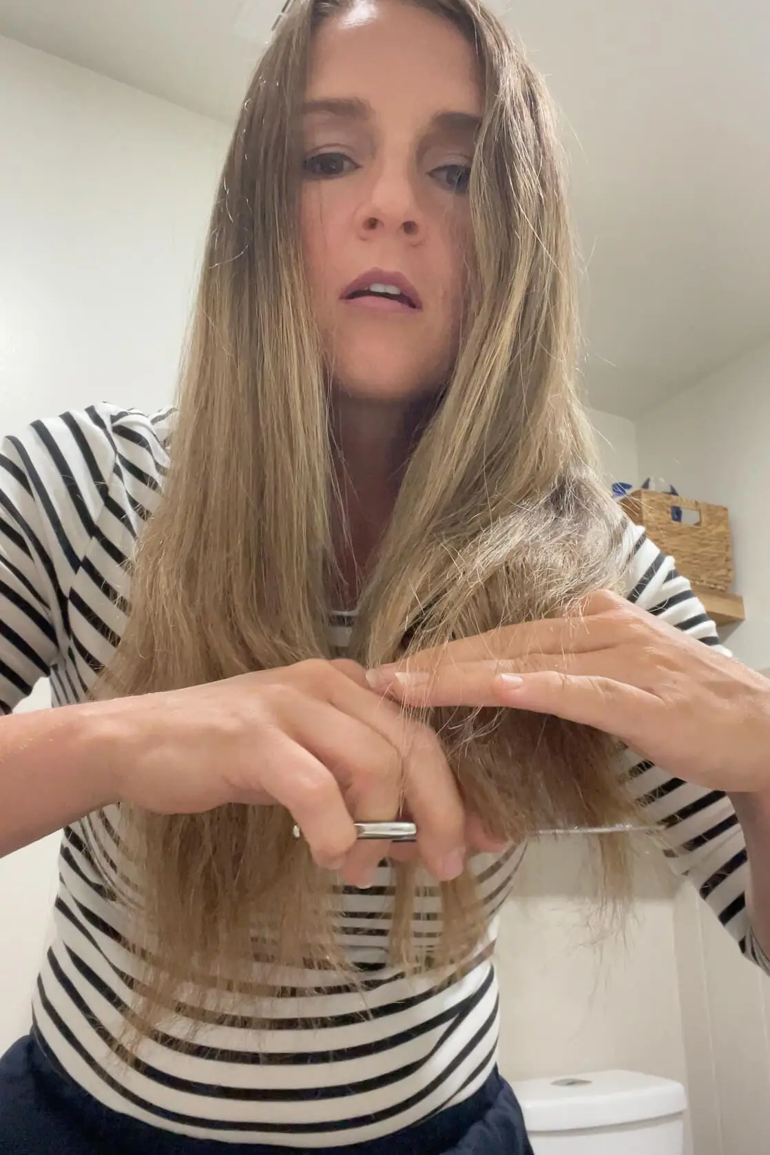 Woman sectioning her hair and trimming the front to create face-framing shape at home.
