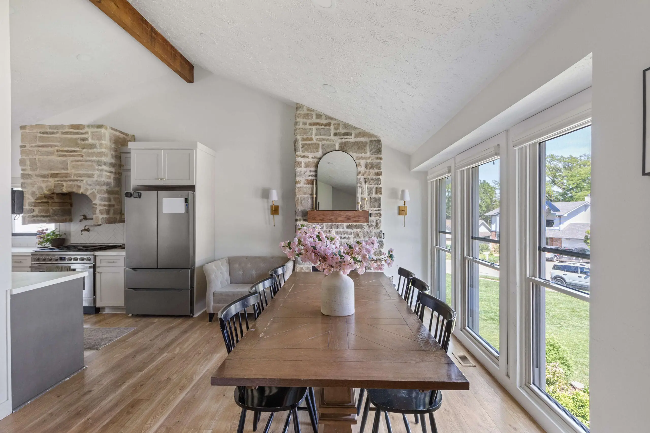 Bright dining room with wood table, white textured ceiling, and natural stone fireplace