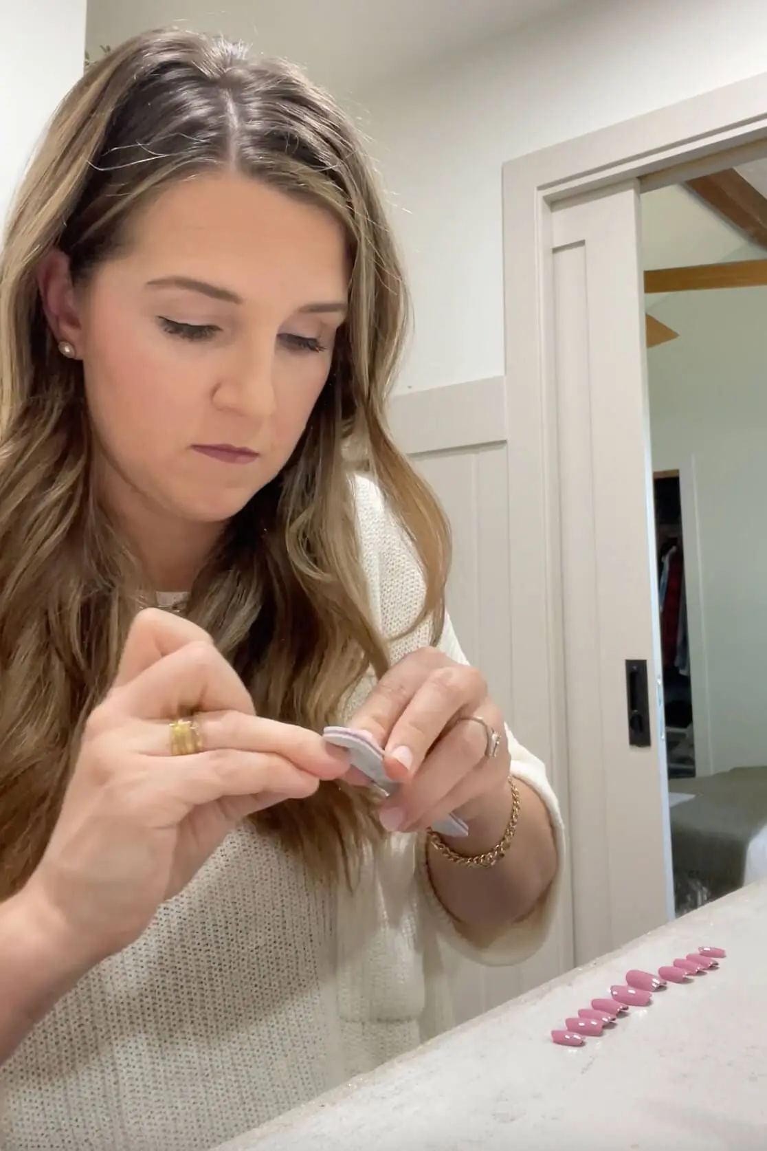 Filing natural nails as part of the prep process before applying Kiss Impress press-on nails at home.