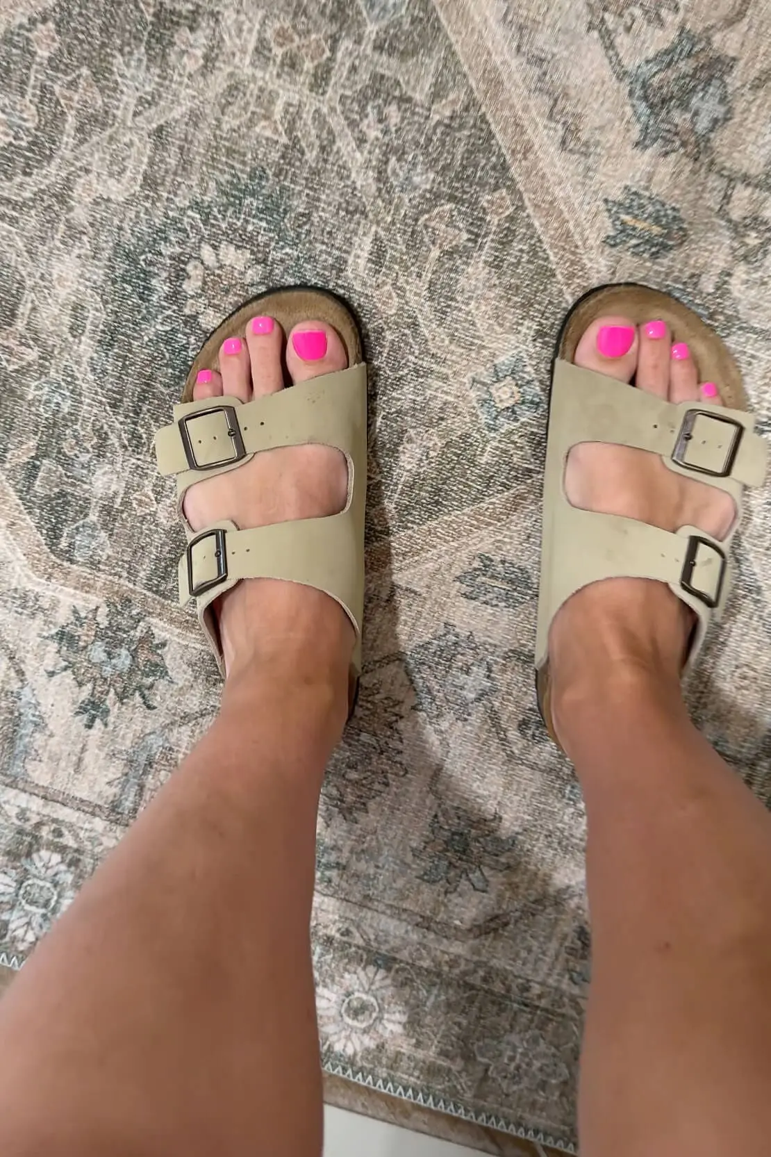 Kiss Impress Nails toe nail set in a bright pink color, worn with sandals and styled on a patterned rug.

