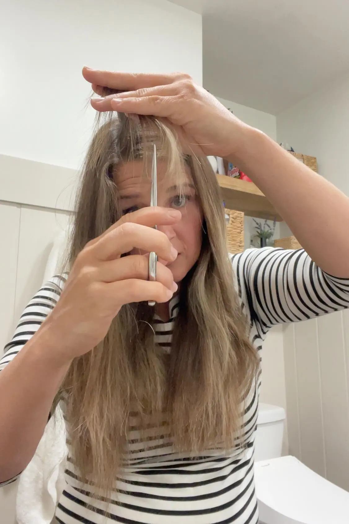 DIY haircut in progress as woman trims the shortest front section near her face.