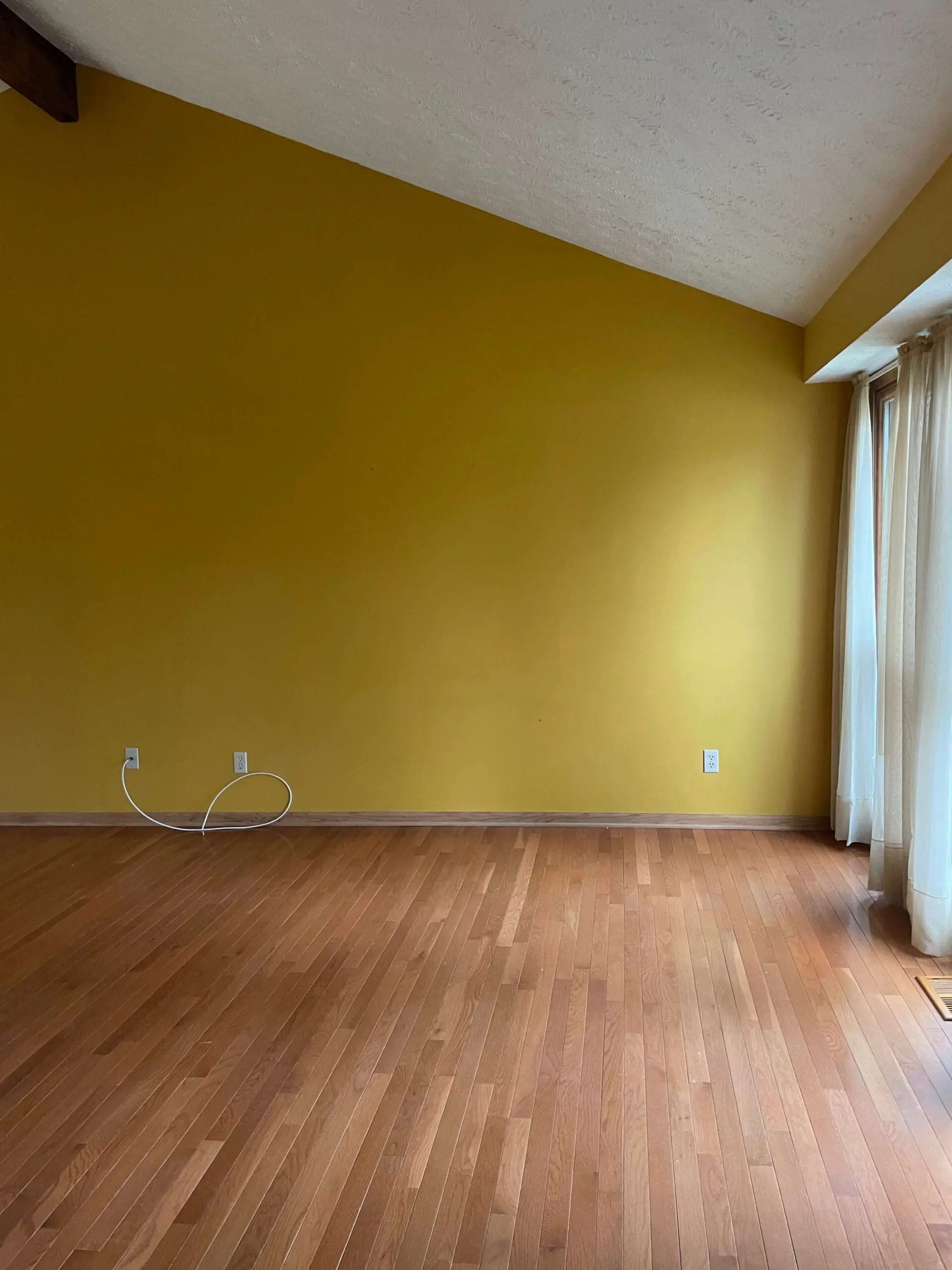 Room with golden yellow walls and textured white ceiling before paint makeover