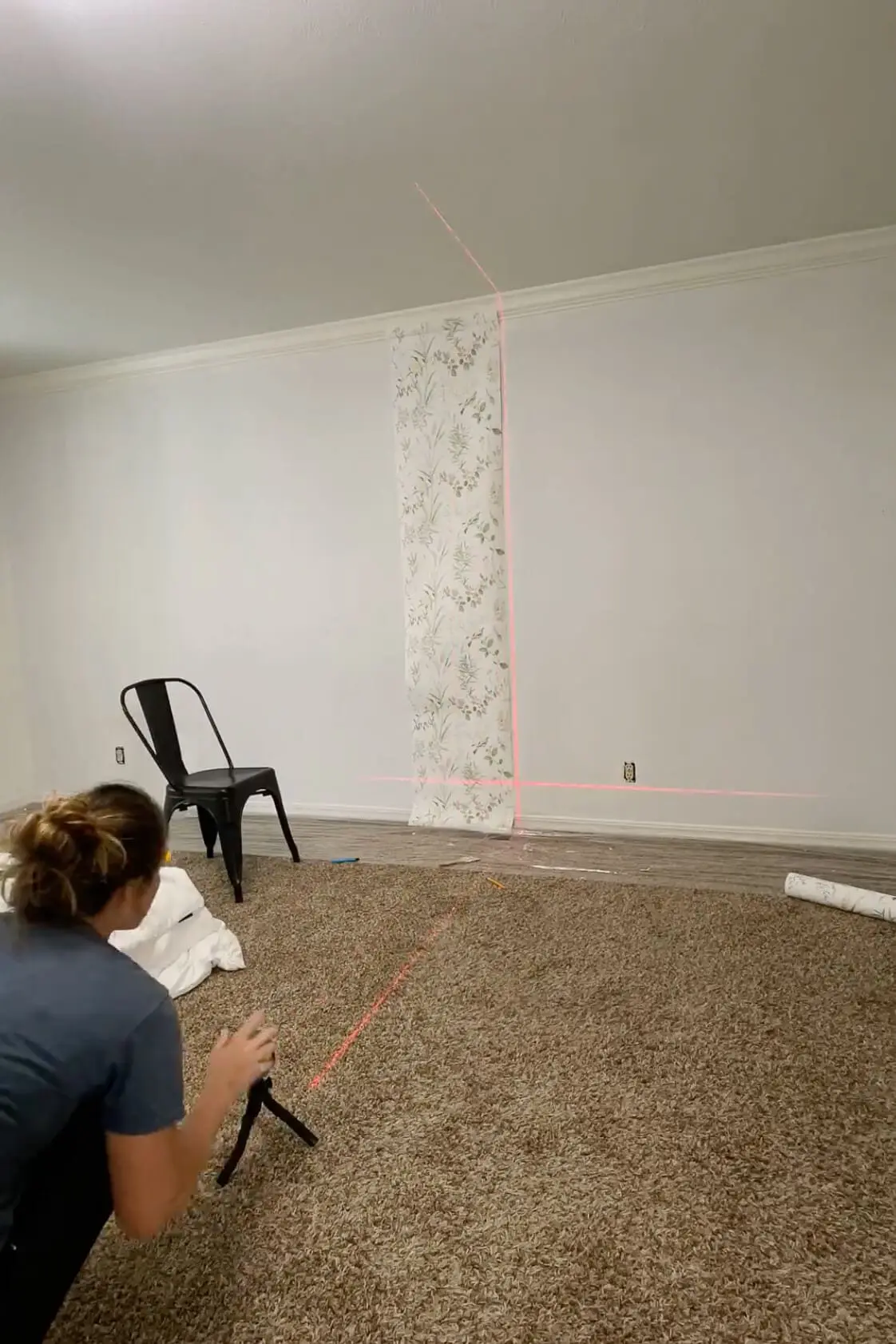 Adjusting a laser level while installing the first panel of traditional wallpaper
