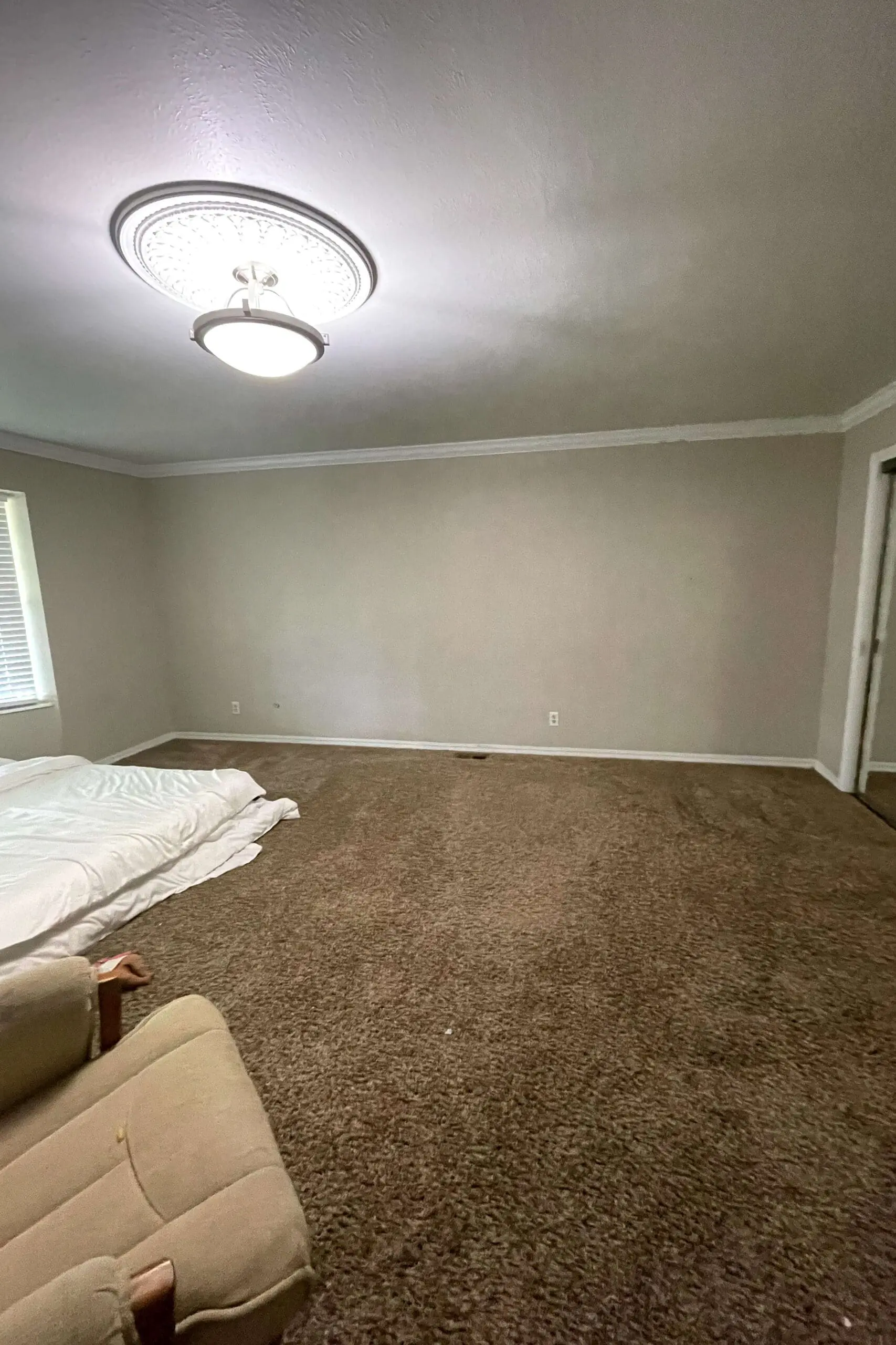 Empty bedroom with beige walls, crown molding, and carpeted floors