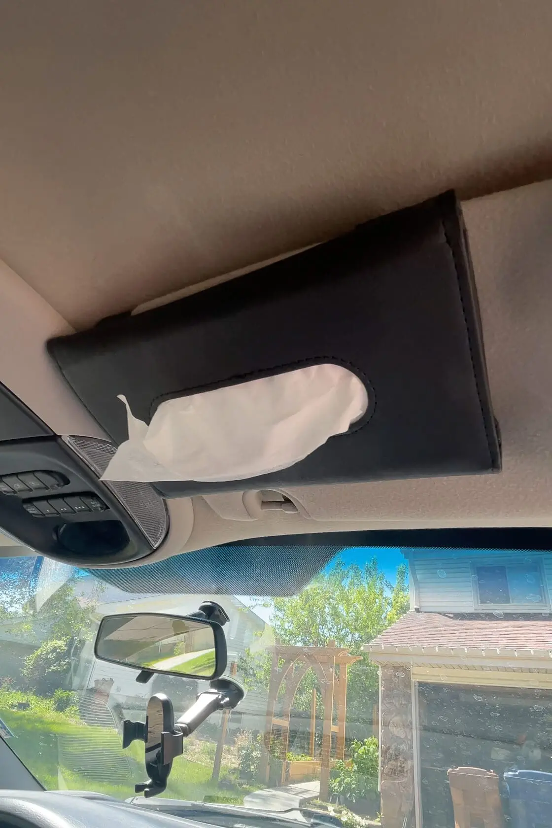 Black leather tissue holder clipped to the car’s sun visor for easy access during road trips or daily drives.
