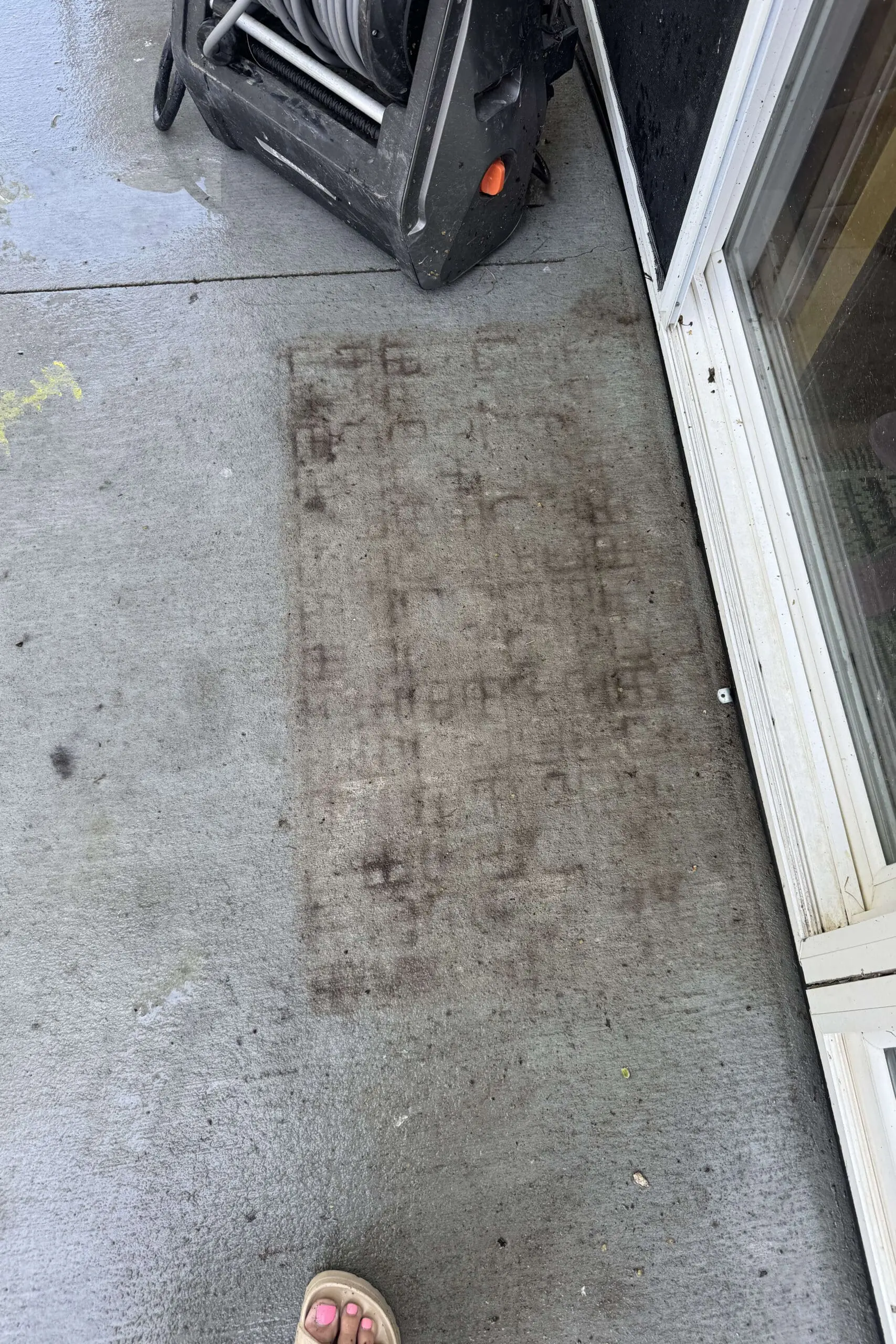 Dark dirty imprint left on concrete patio after moving a door mat near a sliding glass door