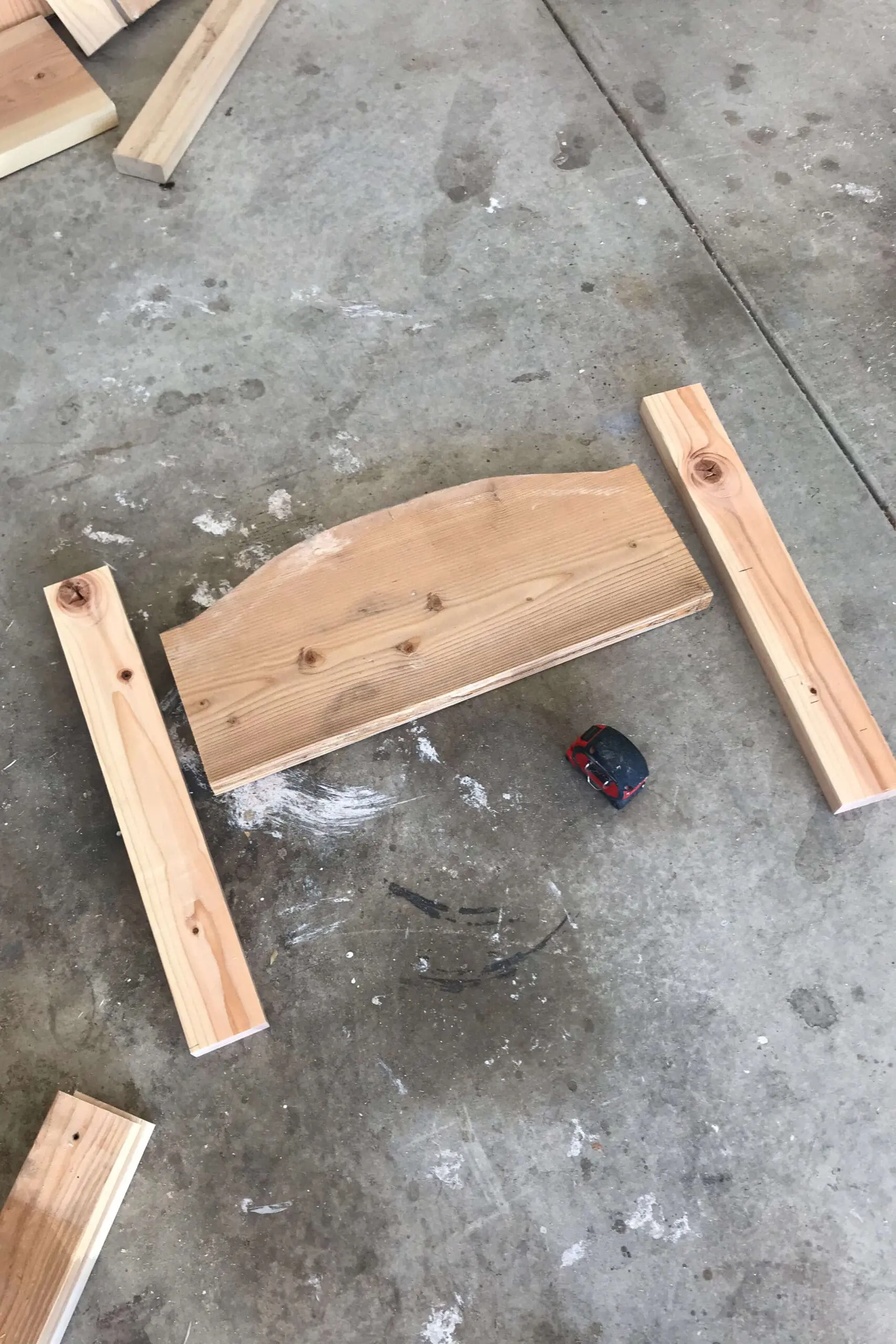 Dry fitting the headboard with scrap wood pieces and a measuring tape during the early stages of a DIY bed frame build.