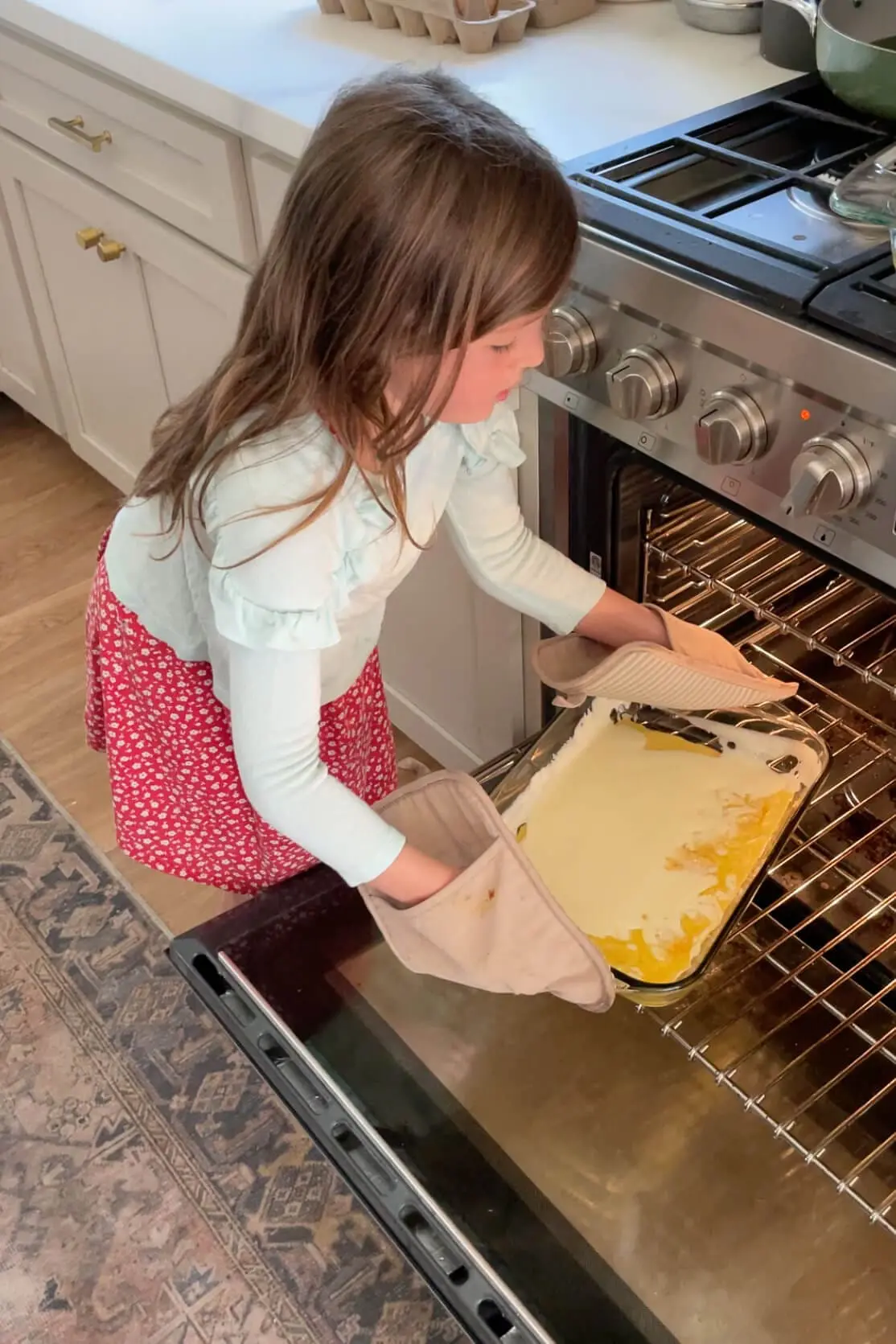 Girl placing a baking dish filled with batter into the oven to bake a Dutch Baby.