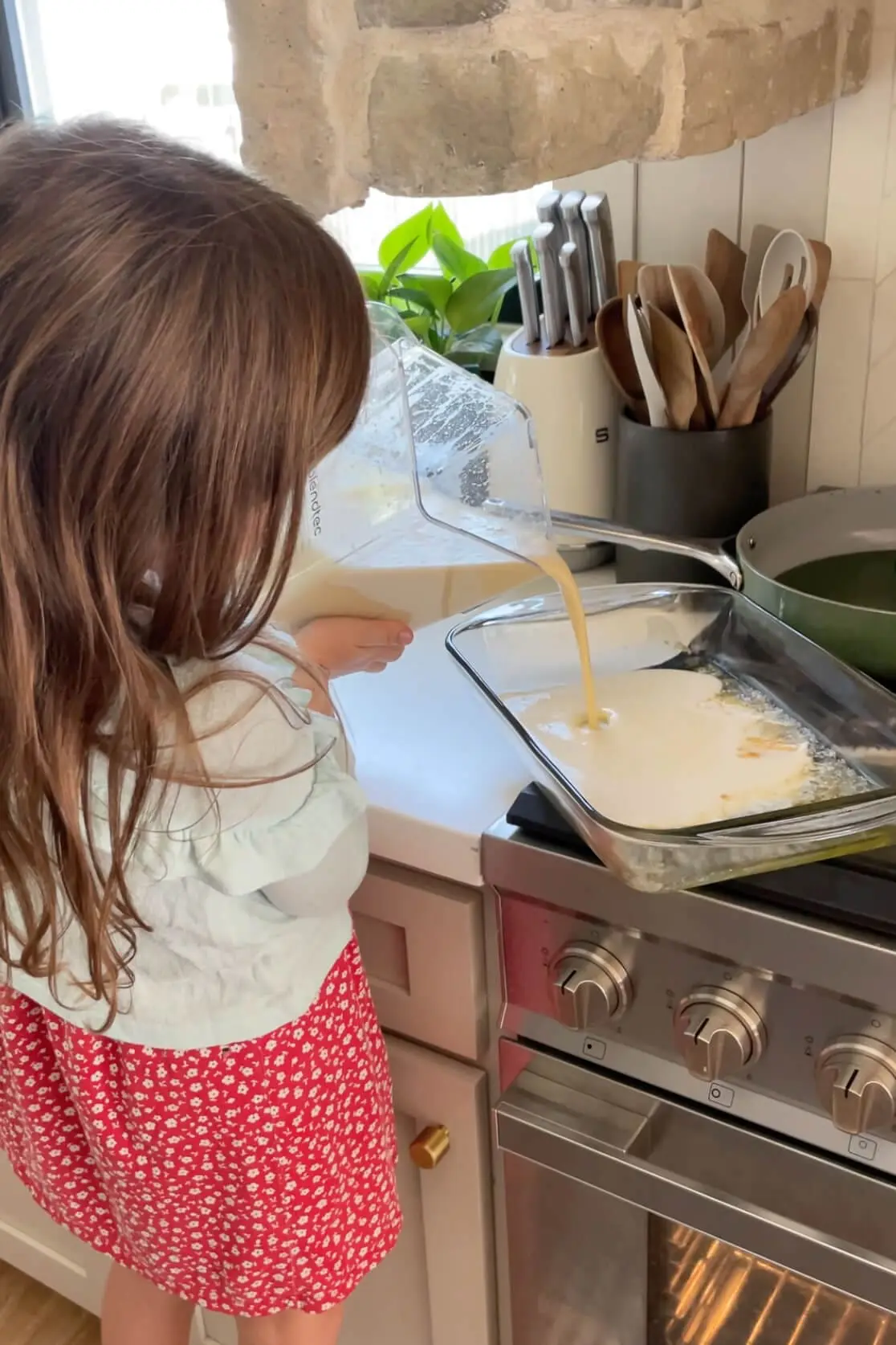Child pouring blended batter into a hot baking dish to make a German Pancake on the stovetop.