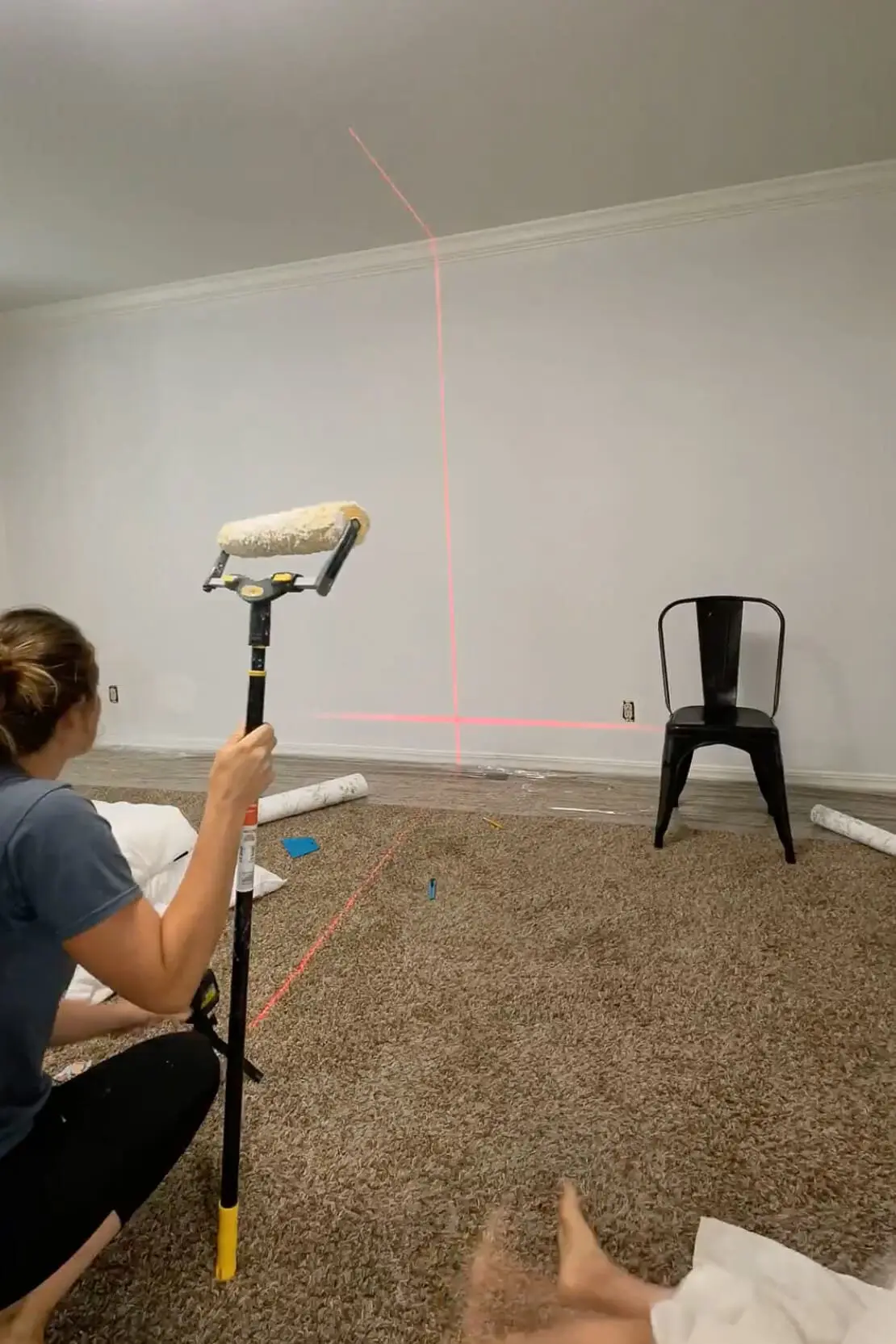 Close-up view of a wallpaper roller and vertical laser line for alignment