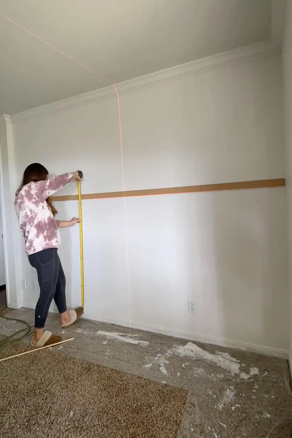 Using a tape measure to determine vertical spacing for trim while planning an easy DIY trim project.