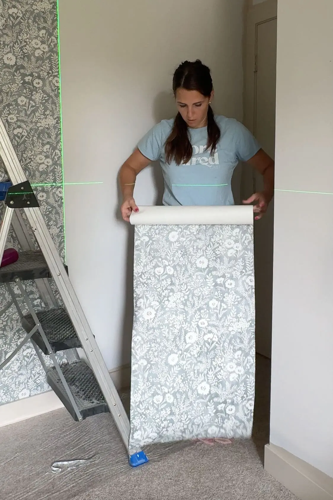 Woman rolling a wallpaper panel with the adhesive side facing out and pattern side in, preparing it to be soaked in water.