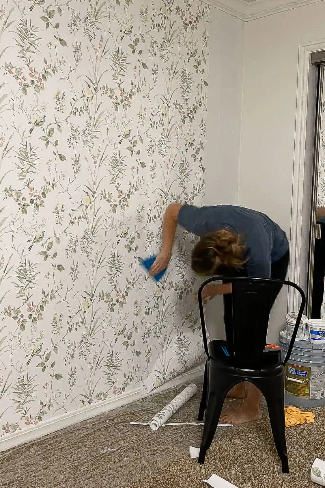 Using a smoothing tool to press traditional wallpaper flat against the wall